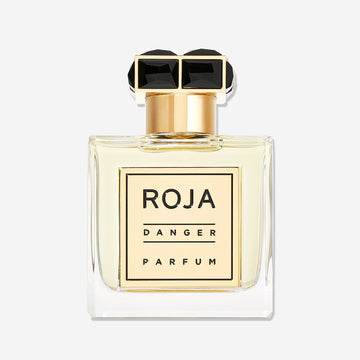 A square glass bottle of Roja Parfums Danger Pour Homme with a gold label and black gemstone-like cap, filled with pale yellow liquid that hints at lavender, displayed against a plain white background.