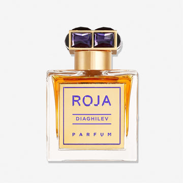 A rectangular glass bottle of Diaghilev by Roja Parfums with amber liquid, a gold and purple label, and a gold cap adorned with two purple gem-like accents, highlighting this luxurious Chypré fragrance.