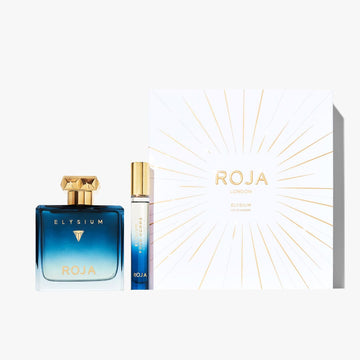 A blue gradient glass bottle and matching travel spray from the Elysium Pour Homme Festive Gift Set by Roja Parfums are displayed beside a white box with gold sunburst, embodying this luxurious men’s fragrance.