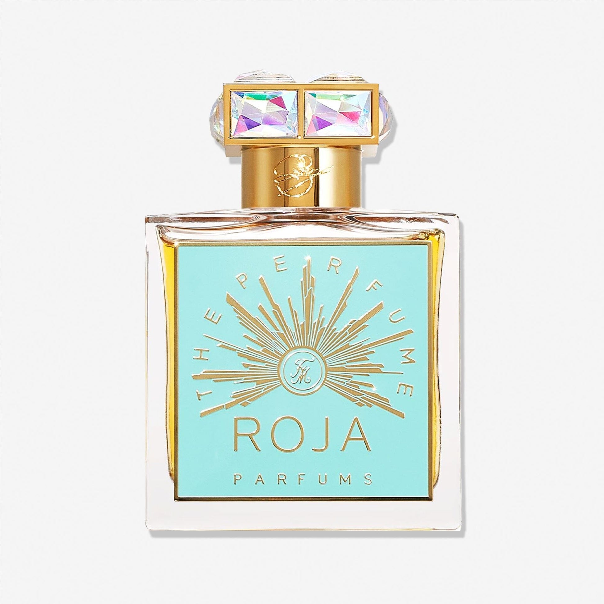A square glass perfume bottle by Roja Parfums for Fortnum & Mason features a gold and turquoise label, a gold cap crowned with two iridescent square gems, and a sunburst design evoking rich vanilla and amber notes.