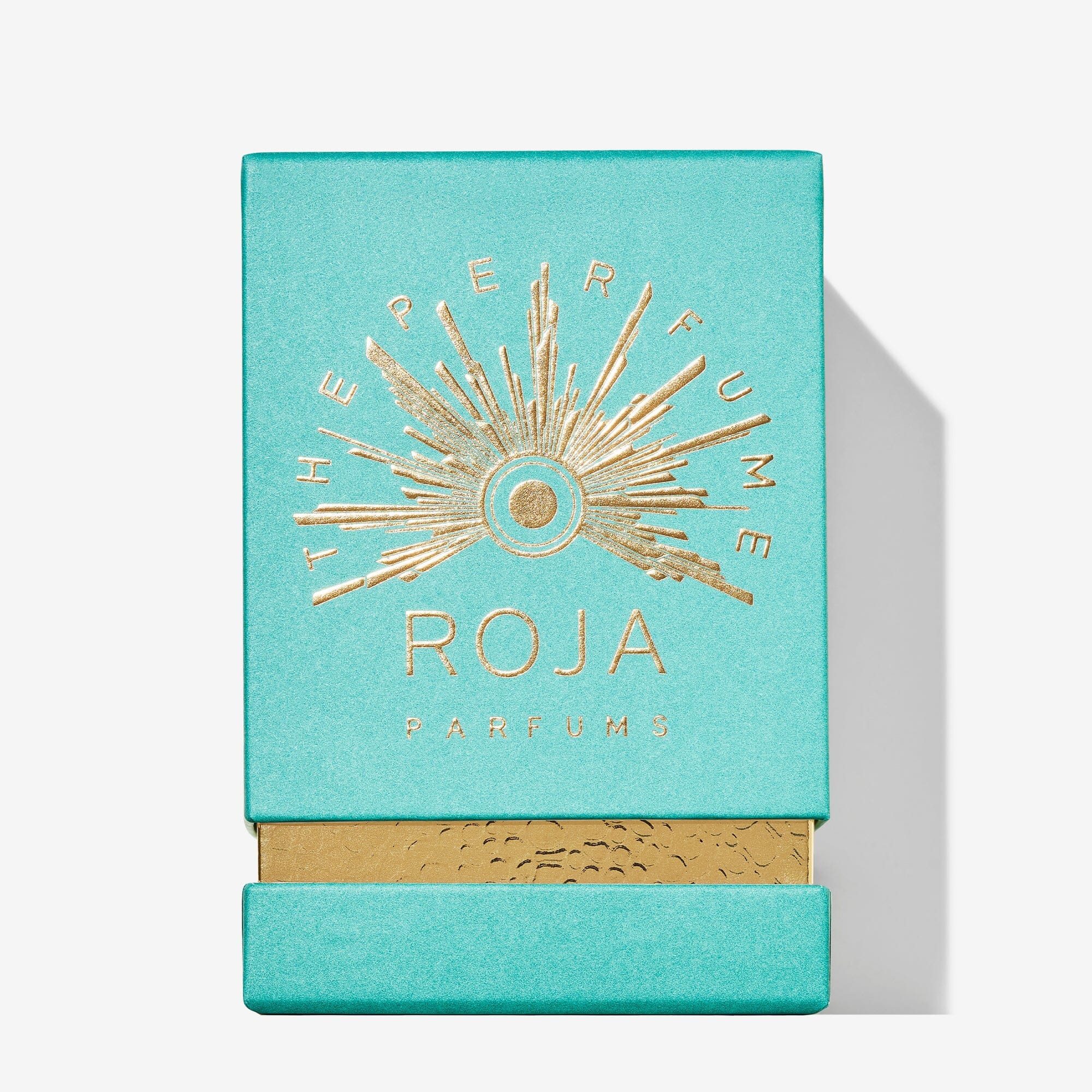 A turquoise box with gold embossed text and a sunburst design reads “Fortnum & Mason Roja Parfums,” hinting at an ambrée perfume inside. The bottom displays a gold accent, and the box is photographed against a white background.
