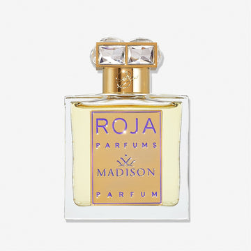 A clear glass bottle labeled Roja Parfums Madison Pour Femme features a gold and purple front plate and a cap adorned with two square, crystal-like gems, hinting at an elegant rose perfume with subtle notes of sandalwood.