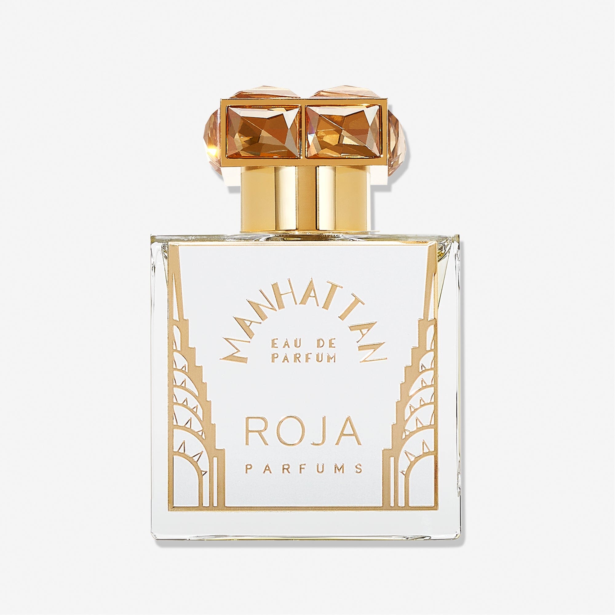 A clear glass bottle of Manhattan by Roja Parfums, a city-inspired Eau de Parfum featuring gold Art Deco designs and a gold cap with two square, gem-like accents.