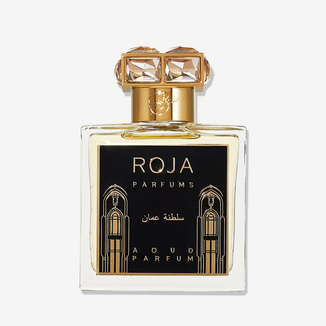 A clear perfume bottle labeled Roja Parfums Sultanate of Oman features gold accents, a black and gold label with Arabic designs, and a crystal-embellished gold cap—evoking luxurious Aoud and smoky frankincense.