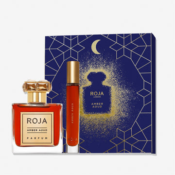 The Amber Aoud Eid Coffret by Roja Parfums is an ideal Eid gift, featuring a square fragrance bottle with gold cap, a slim spray vial, and a dark blue box decorated with gold geometric and moon motifs.