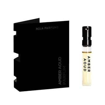A small glass vial labeled Amber Aoud Sample (Gift) from Roja Parfums stands upright beside black card packaging—both perfect as a free gift in your BOGO Bundle from BOGOS.io.
