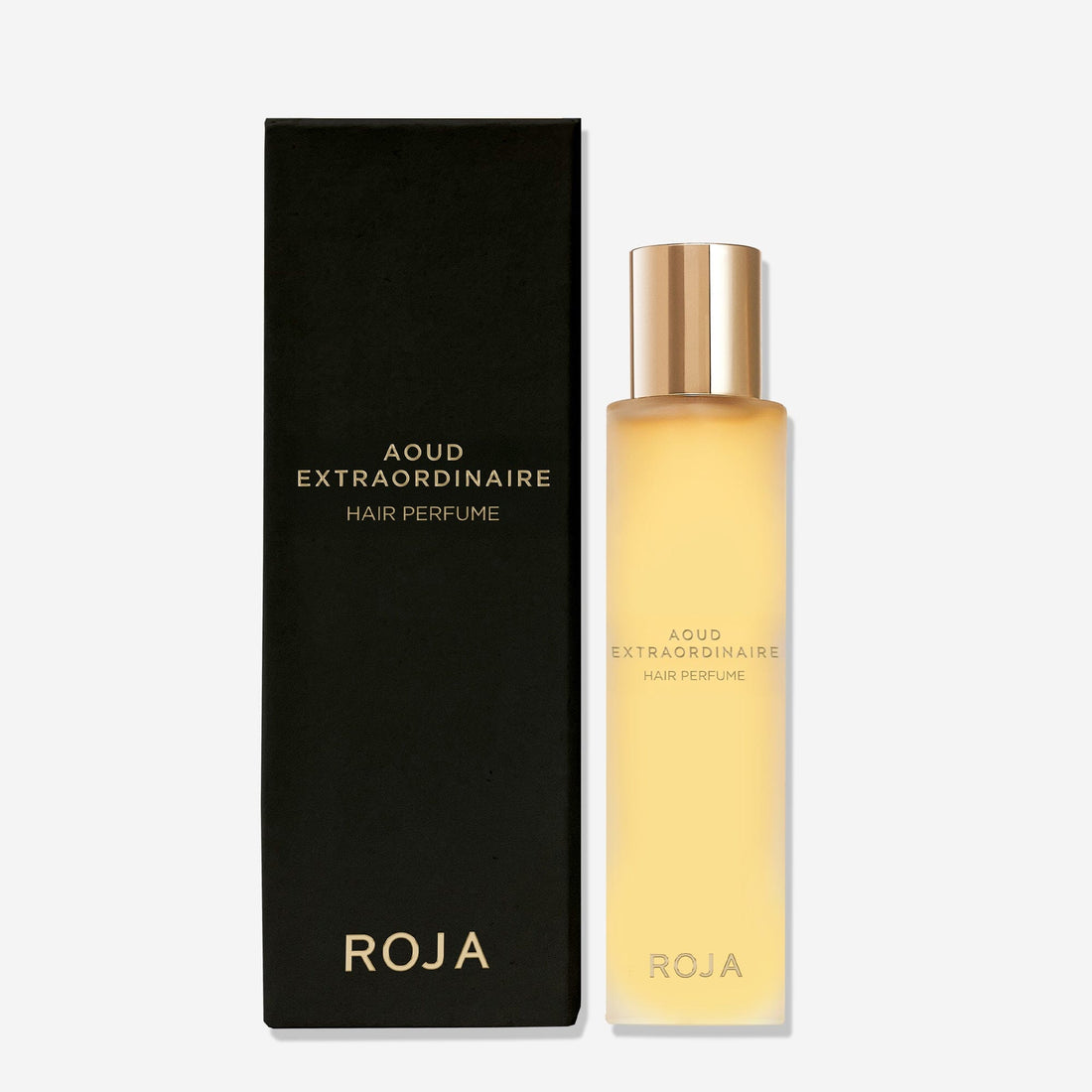 A rectangular black box labeled Aoud Extraordinaire Hair Perfume stands beside a frosted yellow bottle with a gold cap, both featuring Roja Parfums branding—a true luxury fragrance for lovers of fine oud perfume.