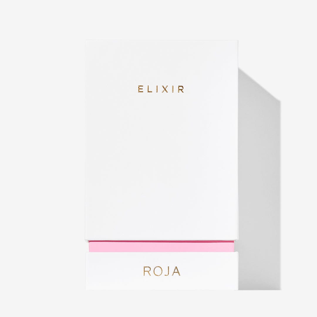 A white rectangular box with gold ELIXIR text and a pink-accented pull-out drawer labeled ROJA PARFUMS holds Elixir Pour Femme, its minimal, elegant design reflecting the ethereal scent of the jewel-adorned bottle inside.