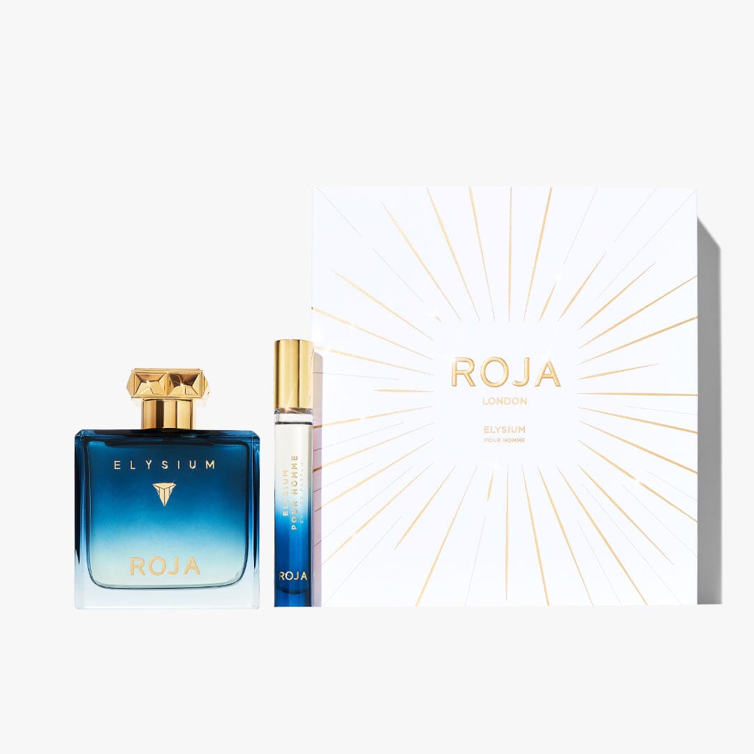 A blue gradient glass bottle and matching travel spray from the Elysium Pour Homme Festive Gift Set by Roja Parfums are displayed beside a white box with gold sunburst, embodying this luxurious men’s fragrance.