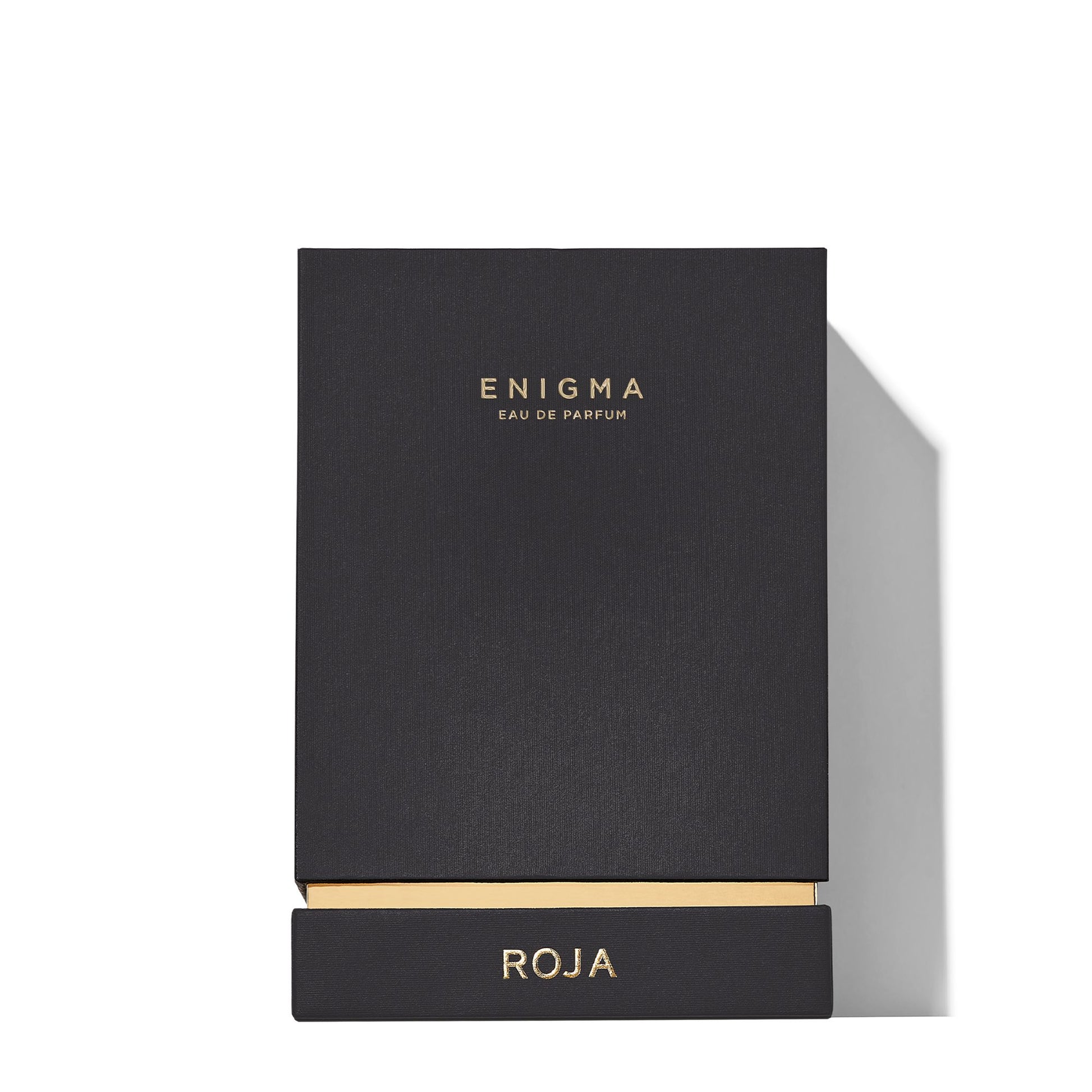 A black rectangular Enigma Gift Set box by Roja Parfums with gold edges and logo, ideal for Art Of Layering, displayed on a white background.