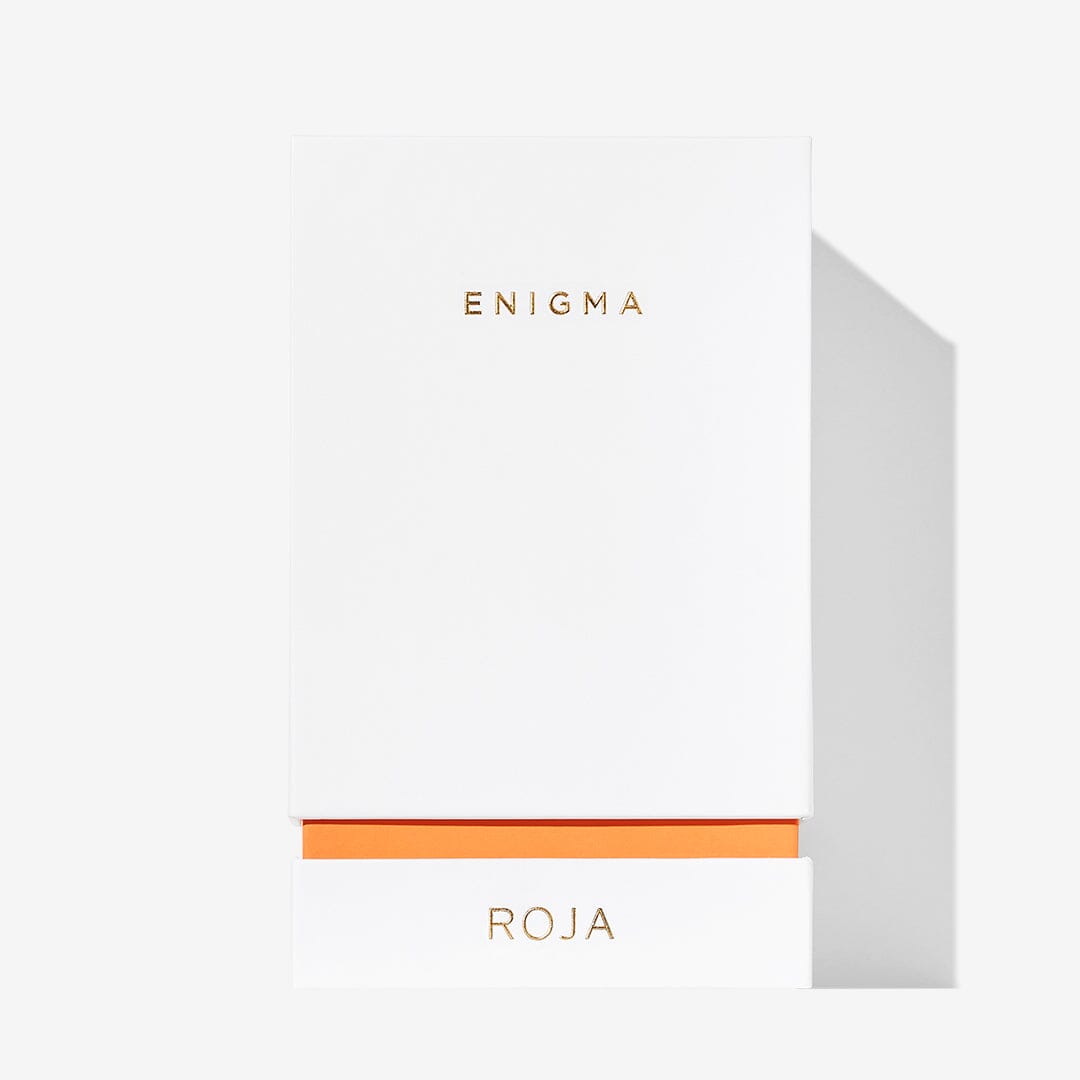A white rectangular box with ENIGMA in gold near the top and ROJA at the bottom, divided by an orange line, hints at the sensual Peach and Sandalwood fragrance of Enigma Pour Femme by Roja Parfums.