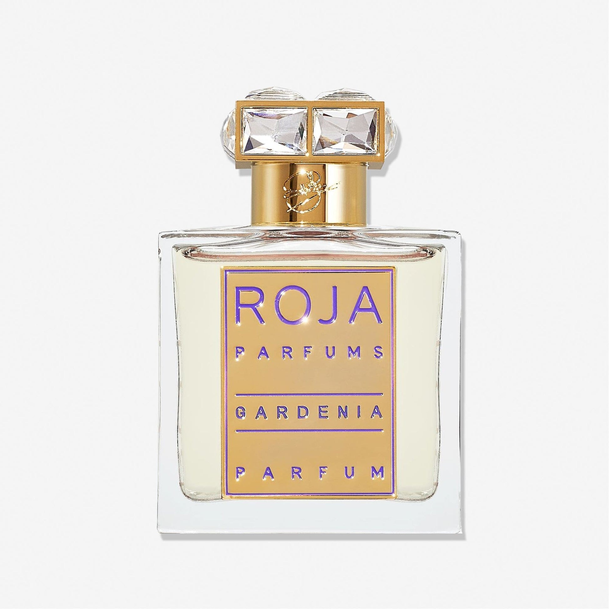 A clear glass perfume bottle with a gold and purple label reading Roja Parfums Gardenia Pour Femme. This elegant white floral scent has a gold cap topped with two large, square, clear gems.