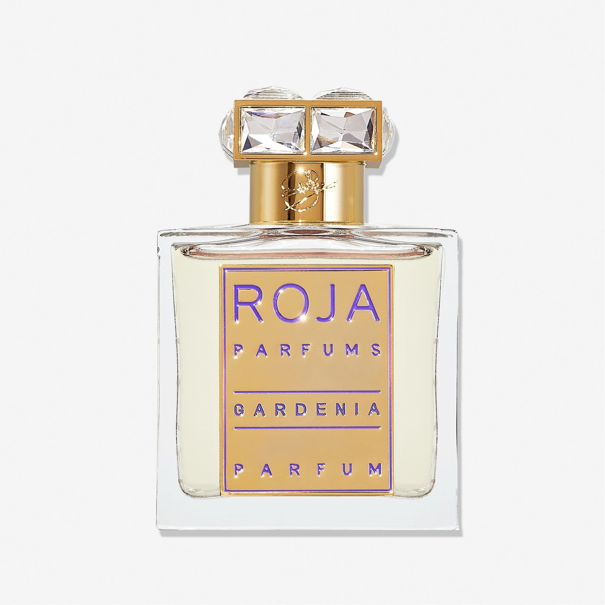 A clear glass perfume bottle with a gold and purple label reading Roja Parfums Gardenia Pour Femme. This elegant white floral scent has a gold cap topped with two large, square, clear gems.