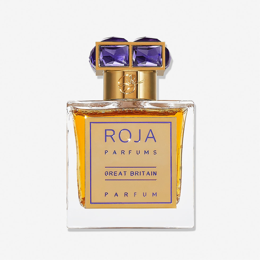 A clear Roja Parfums Great Britain bottle features a gold cap adorned with two large, violet gem-like accents. The amber liquid inside reflects the elegance of this esteemed British parfum.