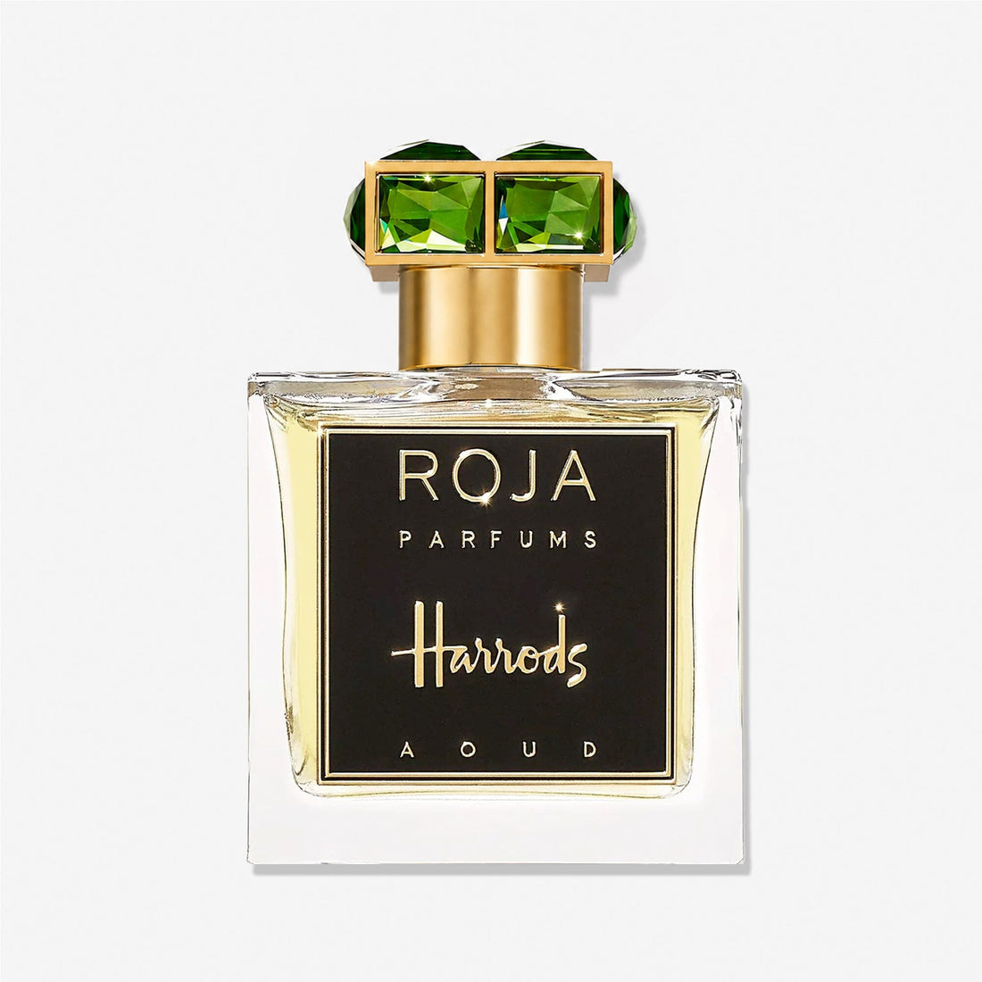 A bottle of Roja Parfums’ Harrods Aoud, a luxury fragrance exclusive to Harrods, featuring a gold cap adorned with two large green gemstones and finished with a black front label.