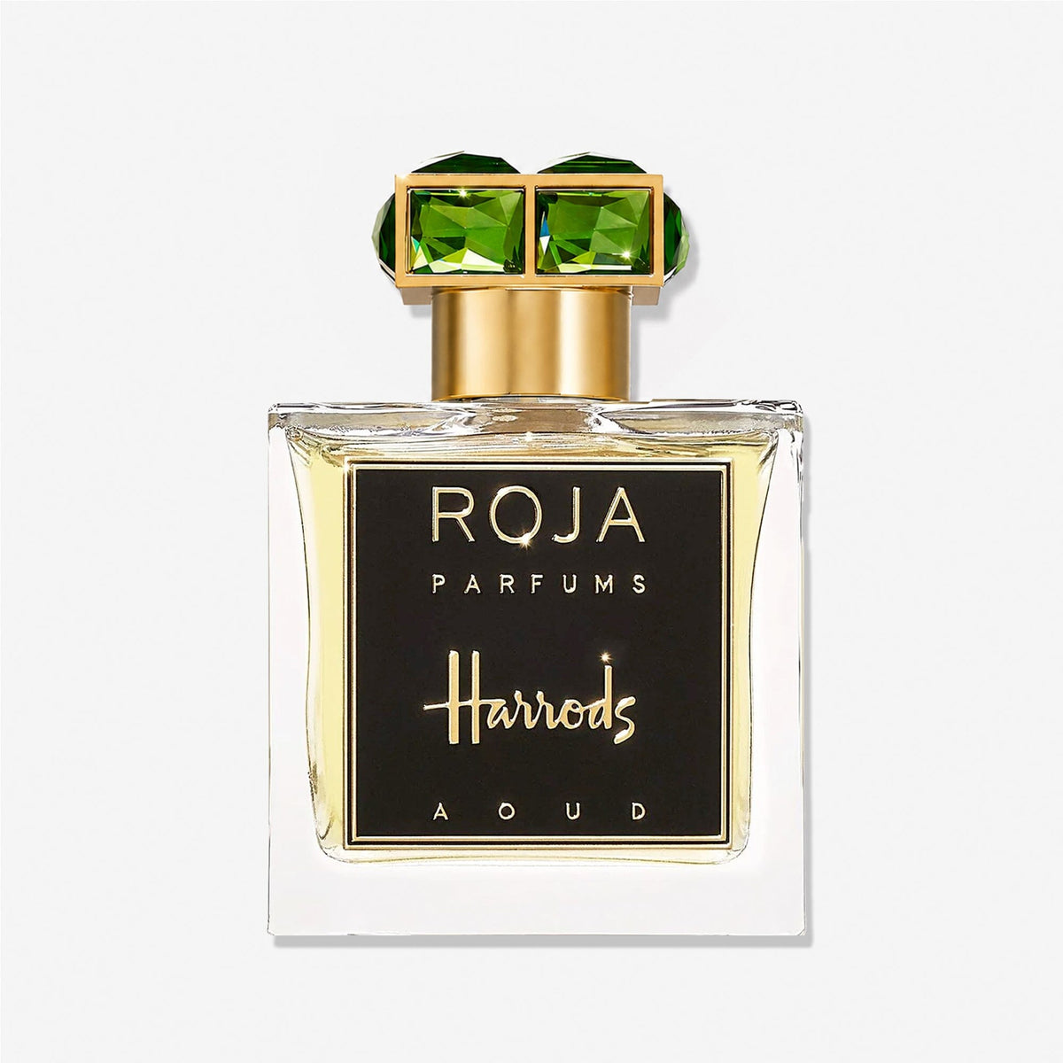 A bottle of Roja Parfums’ Harrods Aoud, a luxury fragrance exclusive to Harrods, featuring a gold cap adorned with two large green gemstones and finished with a black front label.