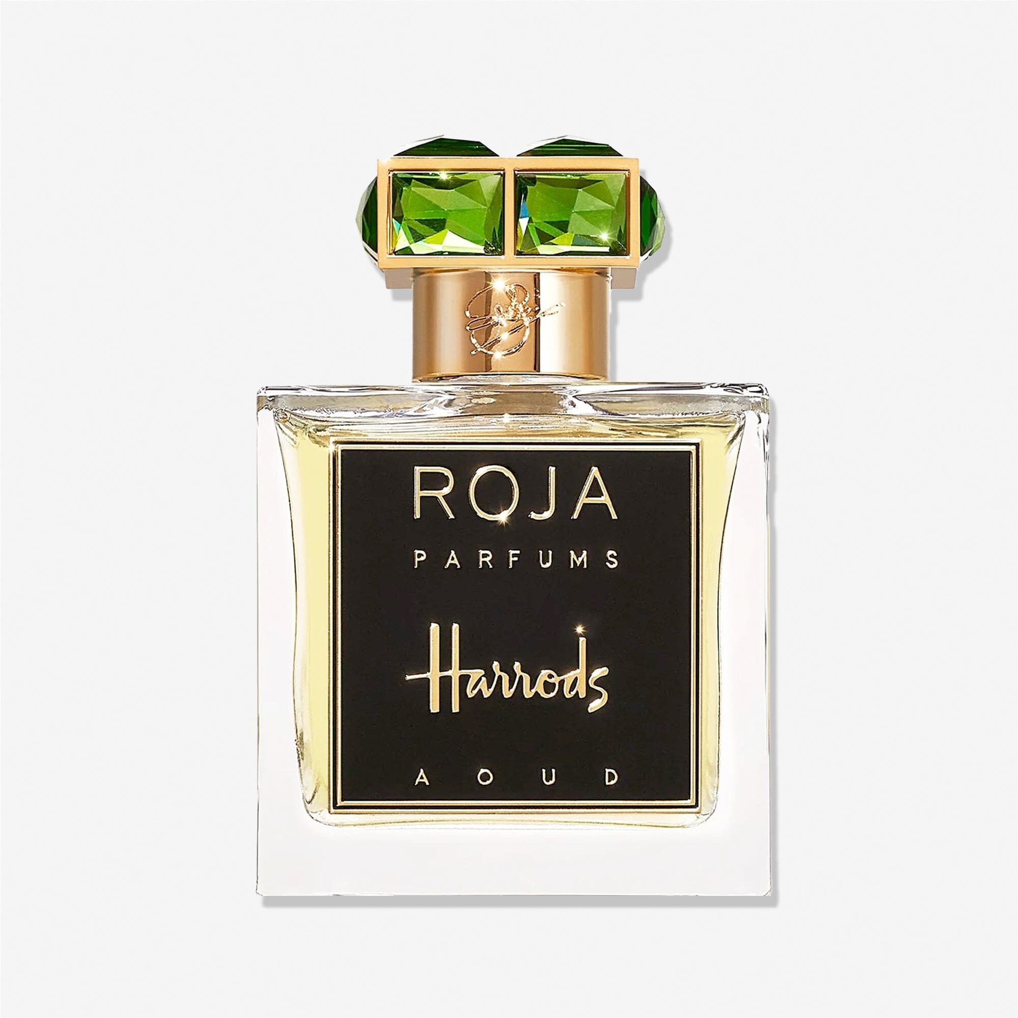 A bottle of Roja Parfums Harrods Aoud perfume features a gold cap with two large green gems and a black and gold label, embodying luxury fragrance.