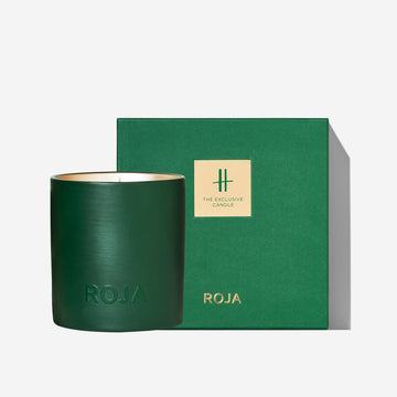 A green candle embossed with ROJA sits beside a matching box with a gold label reading HARRODS MUSK AOUD and the Roja Parfums brand name underneath.