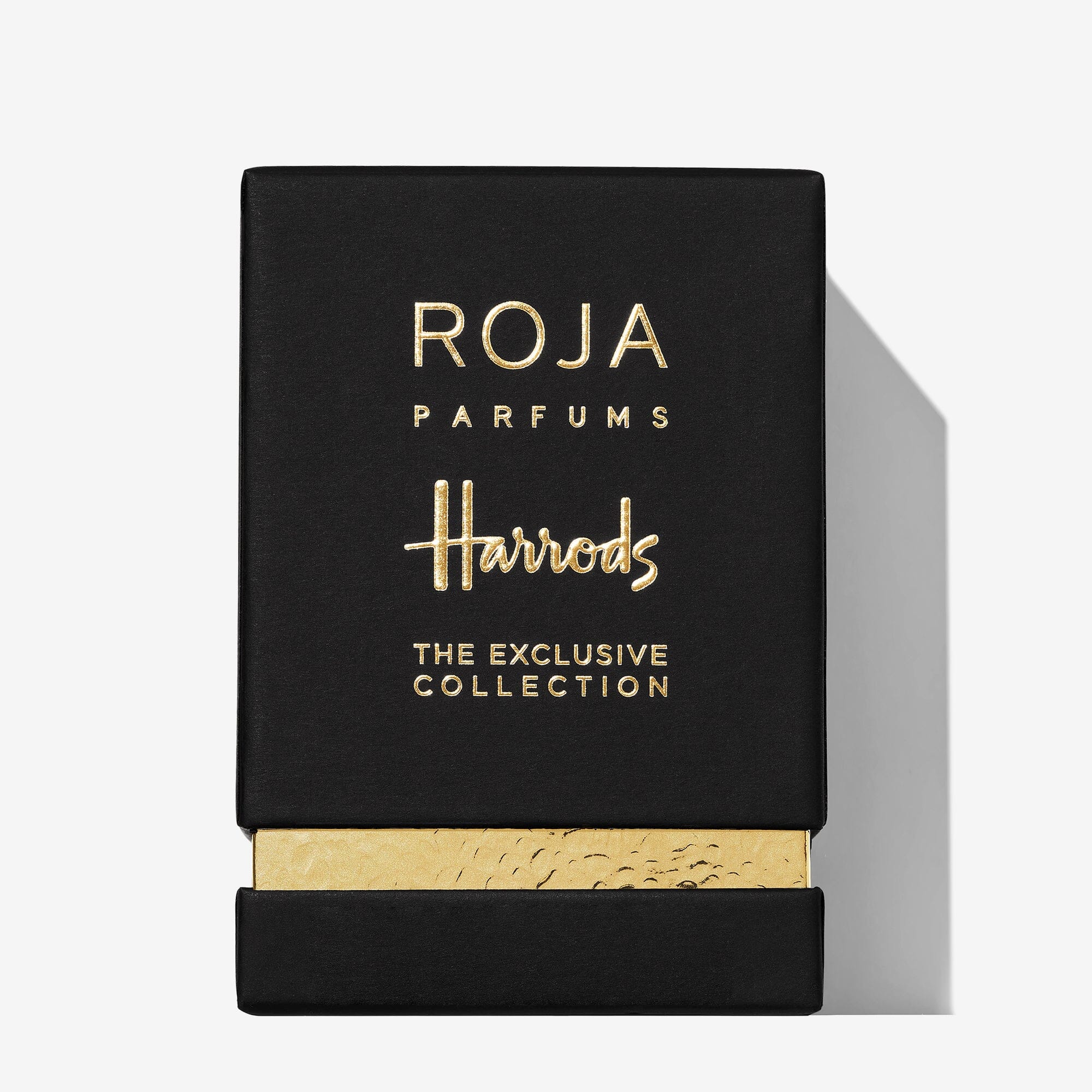 A black rectangular box with gold text reading “Roja Parfums Harrods Pour Homme” and a gold textured strip at the bottom is displayed against a white background, highlighting this luxury men’s fragrance exclusive to Harrods.