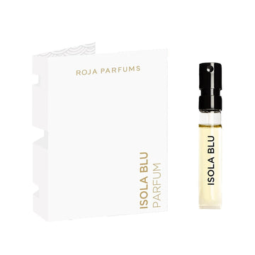 A small spray vial labeled Isola Blu Sample (Gift) from Roja Parfums, filled with pale yellow liquid, stands beside a white card with gold text reading ROJA PARFUMS ISOLA BLU PARFUM.
