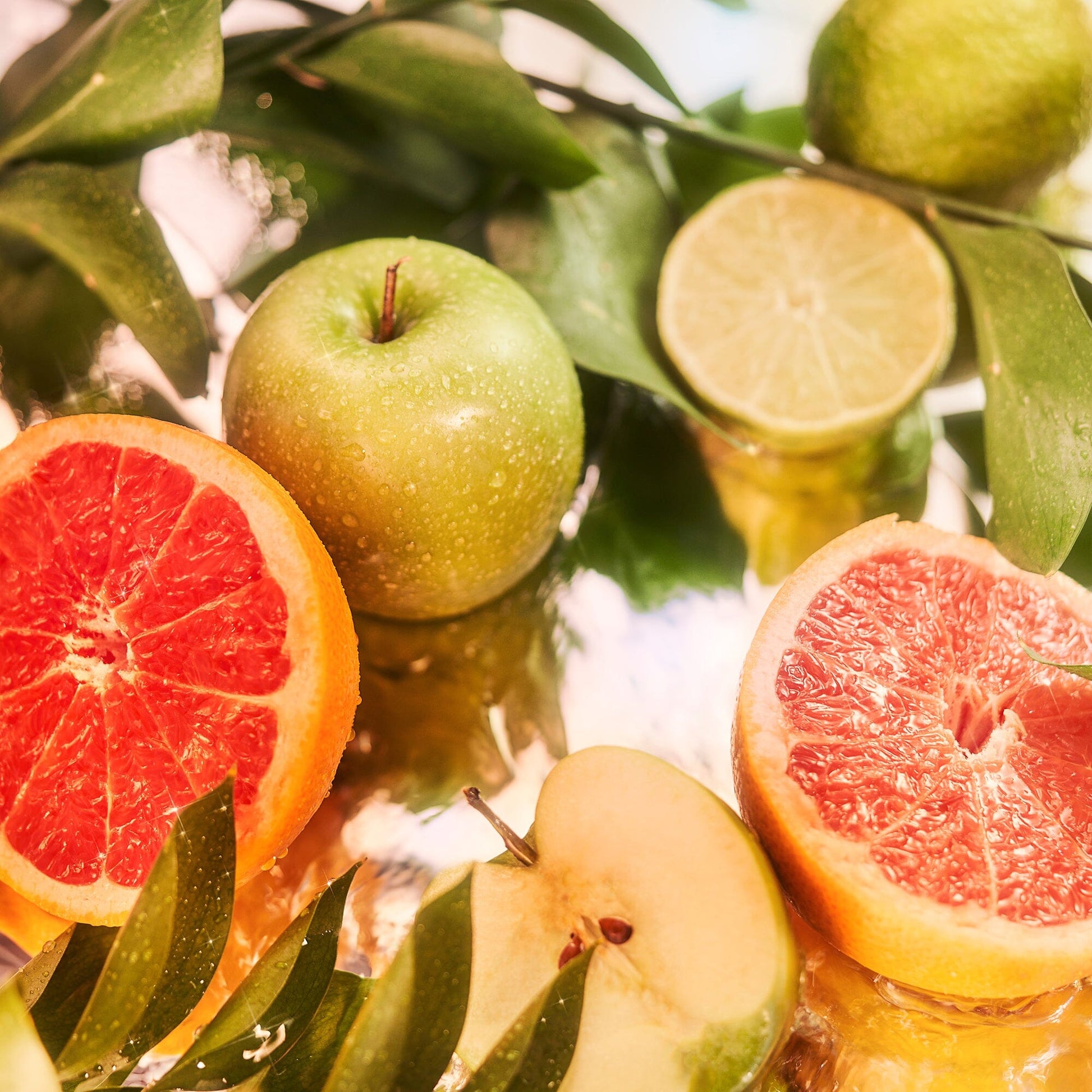A vibrant display of sliced grapefruit, green apple, halved lime, and leaves with water droplets captures the refreshing essence of Isola Blu Sample (Gift) by Roja Parfums.