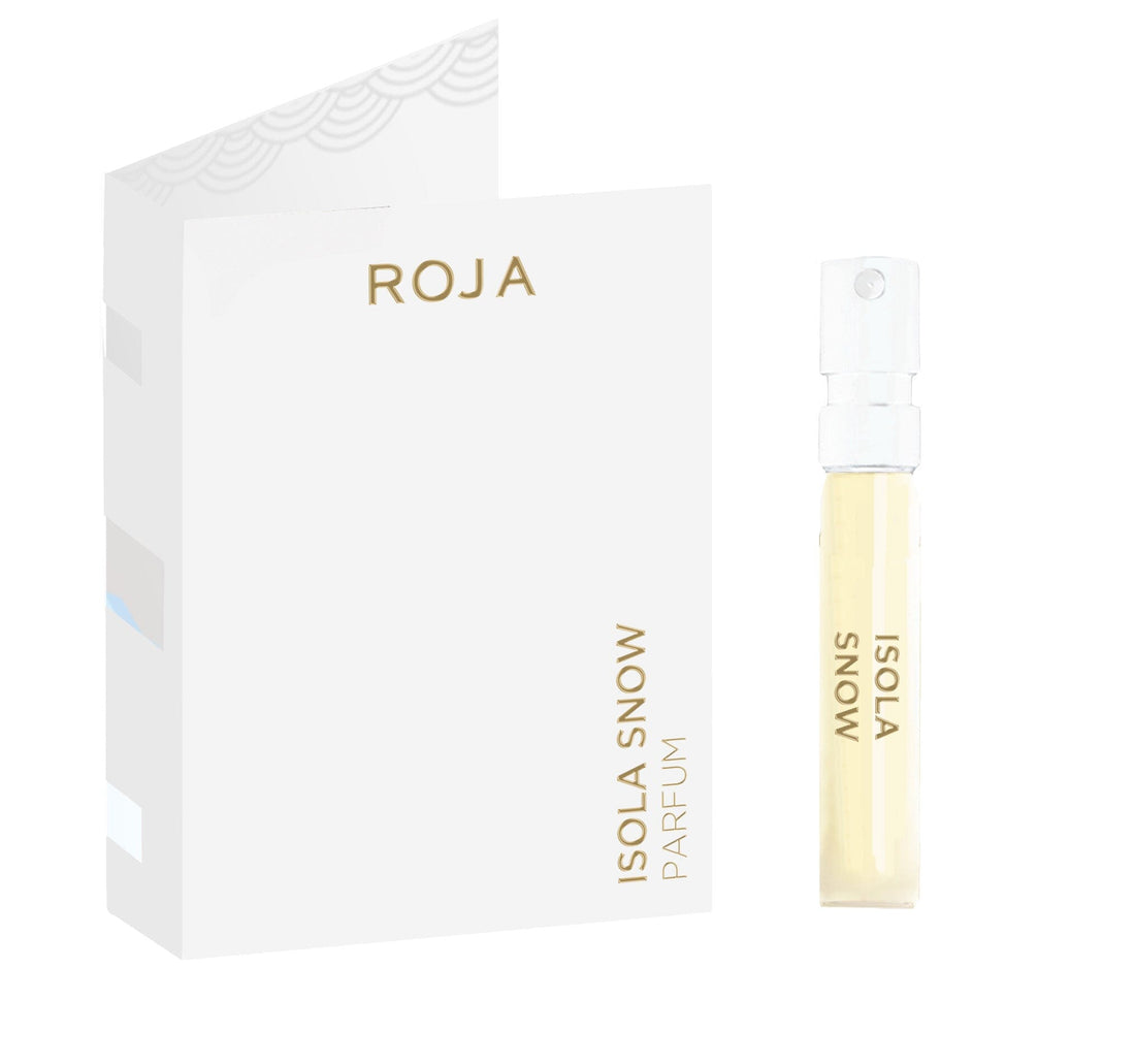 A sample vial labeled Isola Snow Sample (Gift) by Roja Parfums stands next to a white card with gold text reading ROJA and ISOLA SNOW PARFUM, featuring a minimalist design with silver and gold accents.