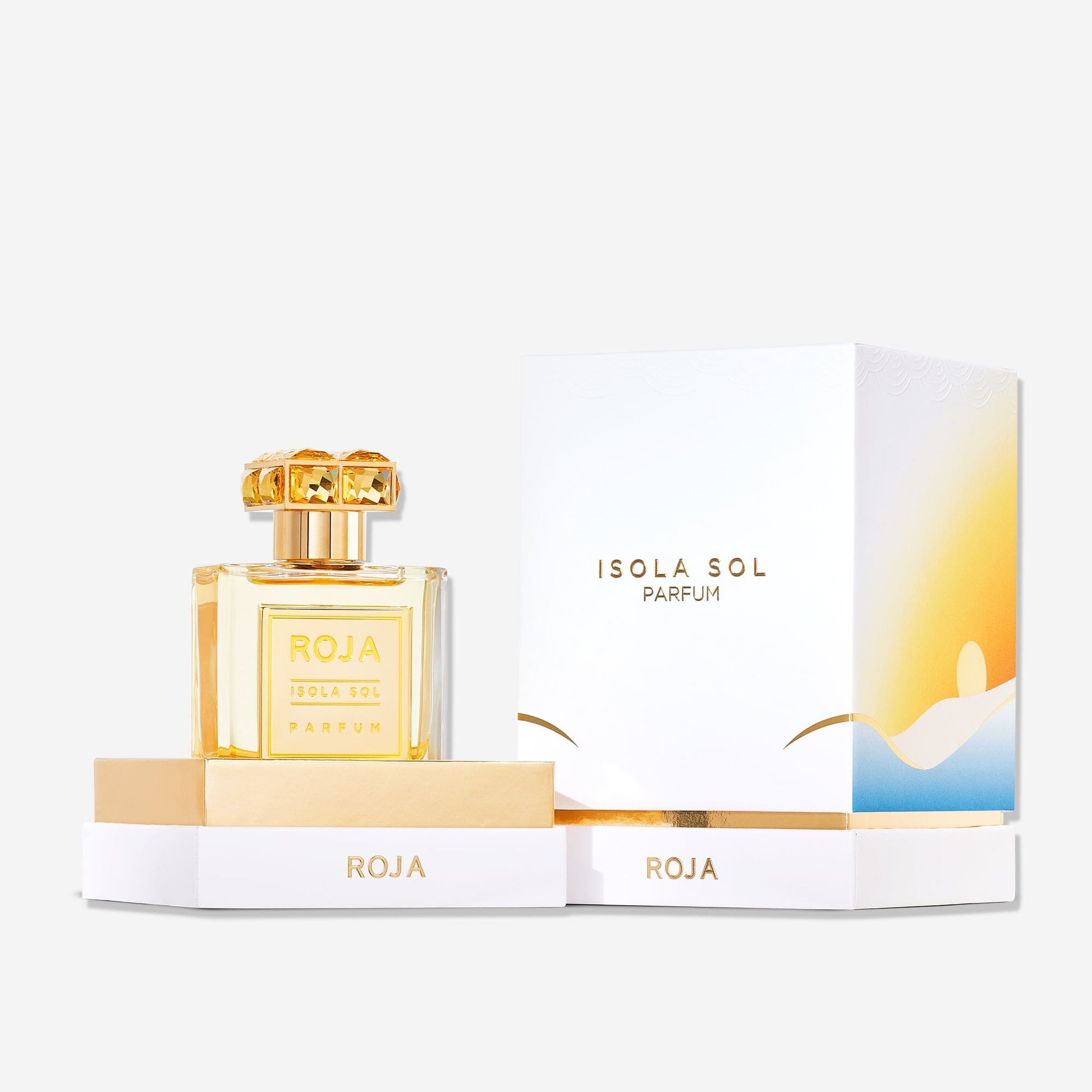 A bottle of Isola Sol by Roja Parfums sits beside its elegant white and gold box, adorned with a minimal sun and landscape design, evoking an island escape. Both are displayed on a matching white and gold base.