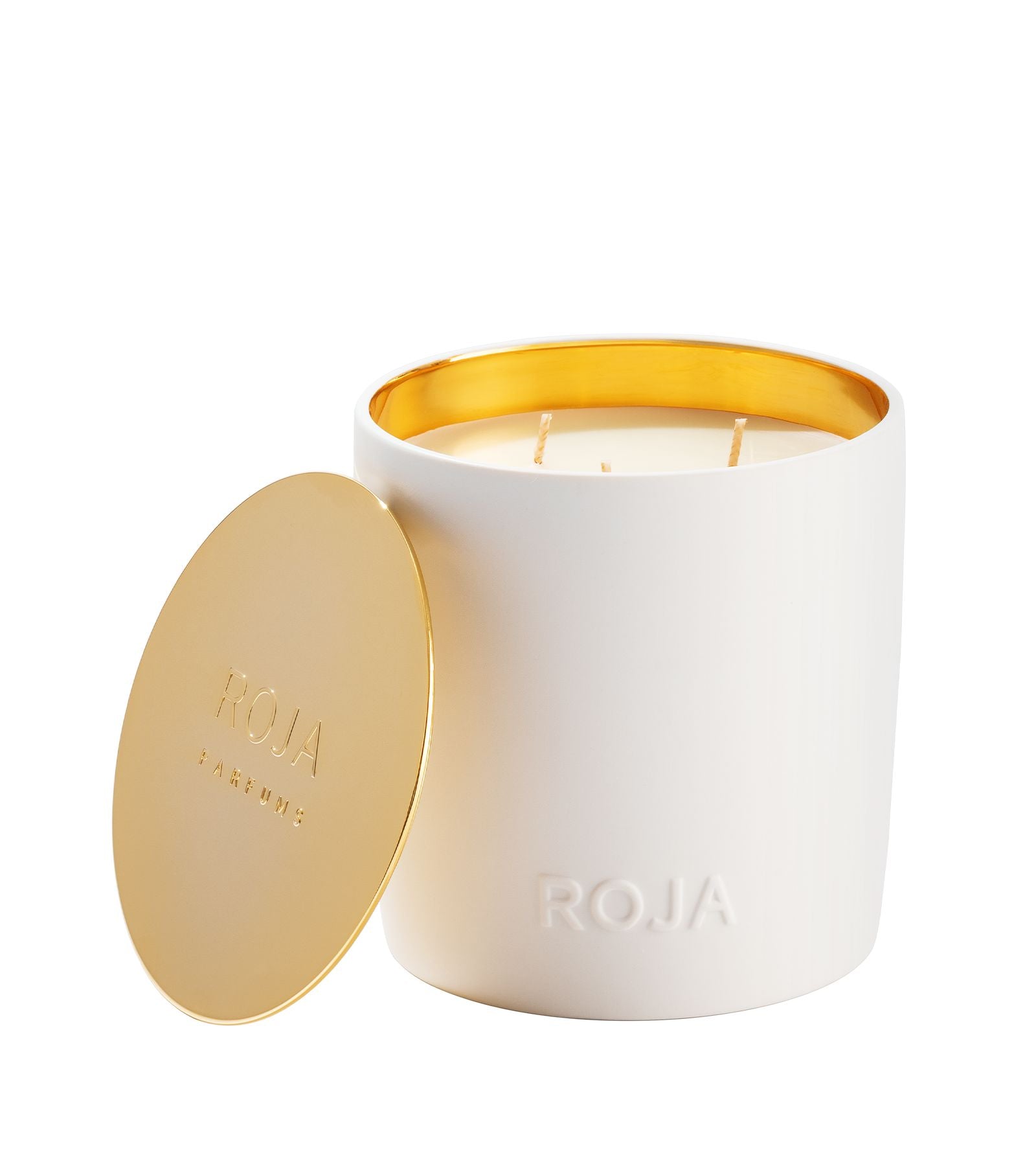 The London candle by Roja Parfums sits in a ceramic holder with a smooth gold interior and lid. The lid, embossed with ROJA PARFUMS, leans against the holder featuring ROJA in raised letters, ideal for evoking Londons sophisticated nightlife.