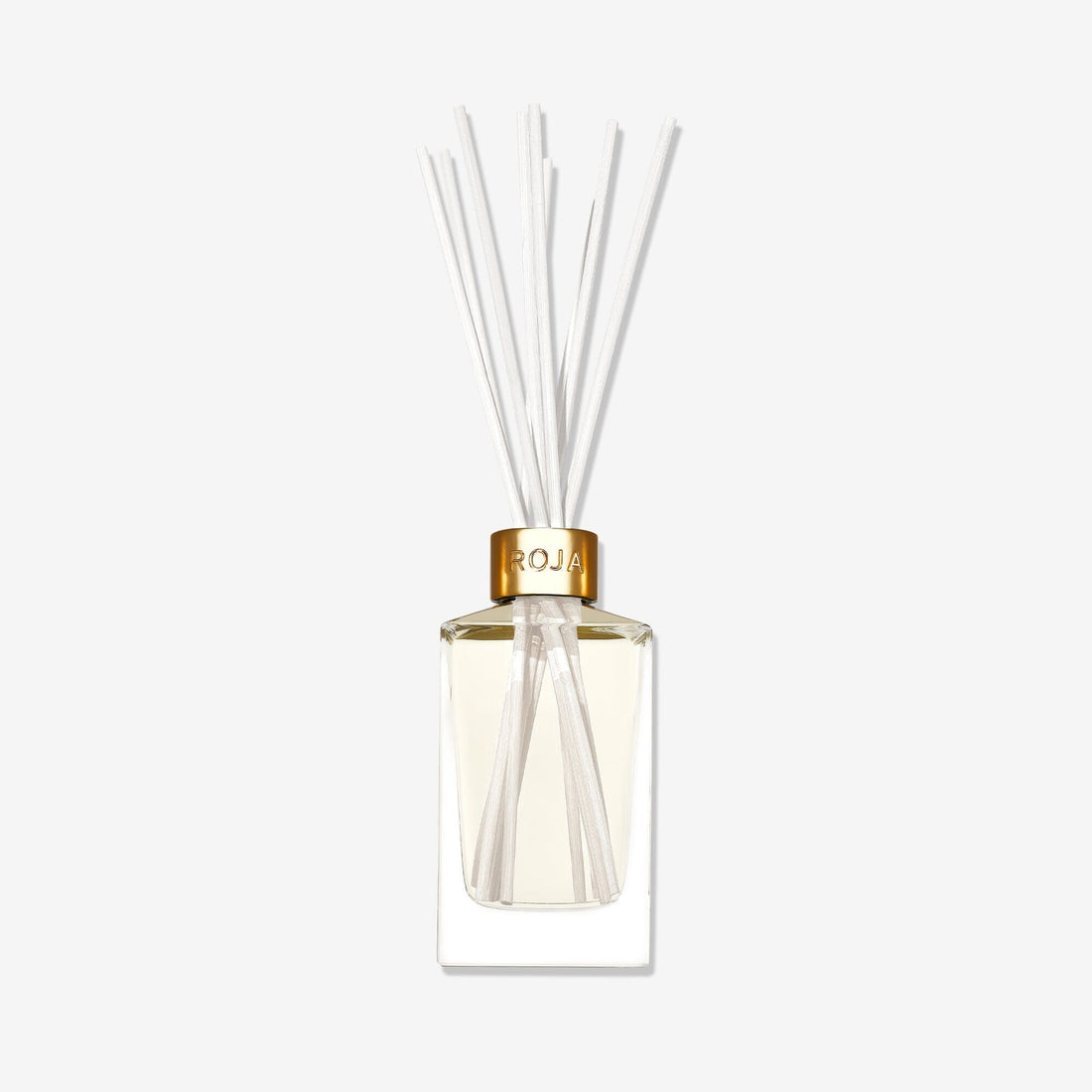 A clear glass reed diffuser labeled "London" by Roja Parfums, featuring a gold cap, light-hued liquid, and white reeds, exudes elegance against a white background.