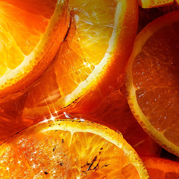 Close-up of bright, juicy orange slices, with sunlight reflecting off their surfaces and highlighting the vibrant orange color and textures. Bubbles and glistening spots add a refreshing, fresh look.