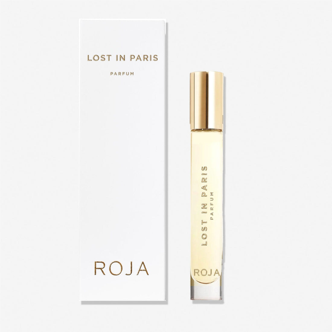 A clear perfume bottle with a gold cap labeled Lost in Paris stands beside its white box, both displaying gold text and the Roja Parfums brand—a tribute to Paris made from luxurious ingredients.