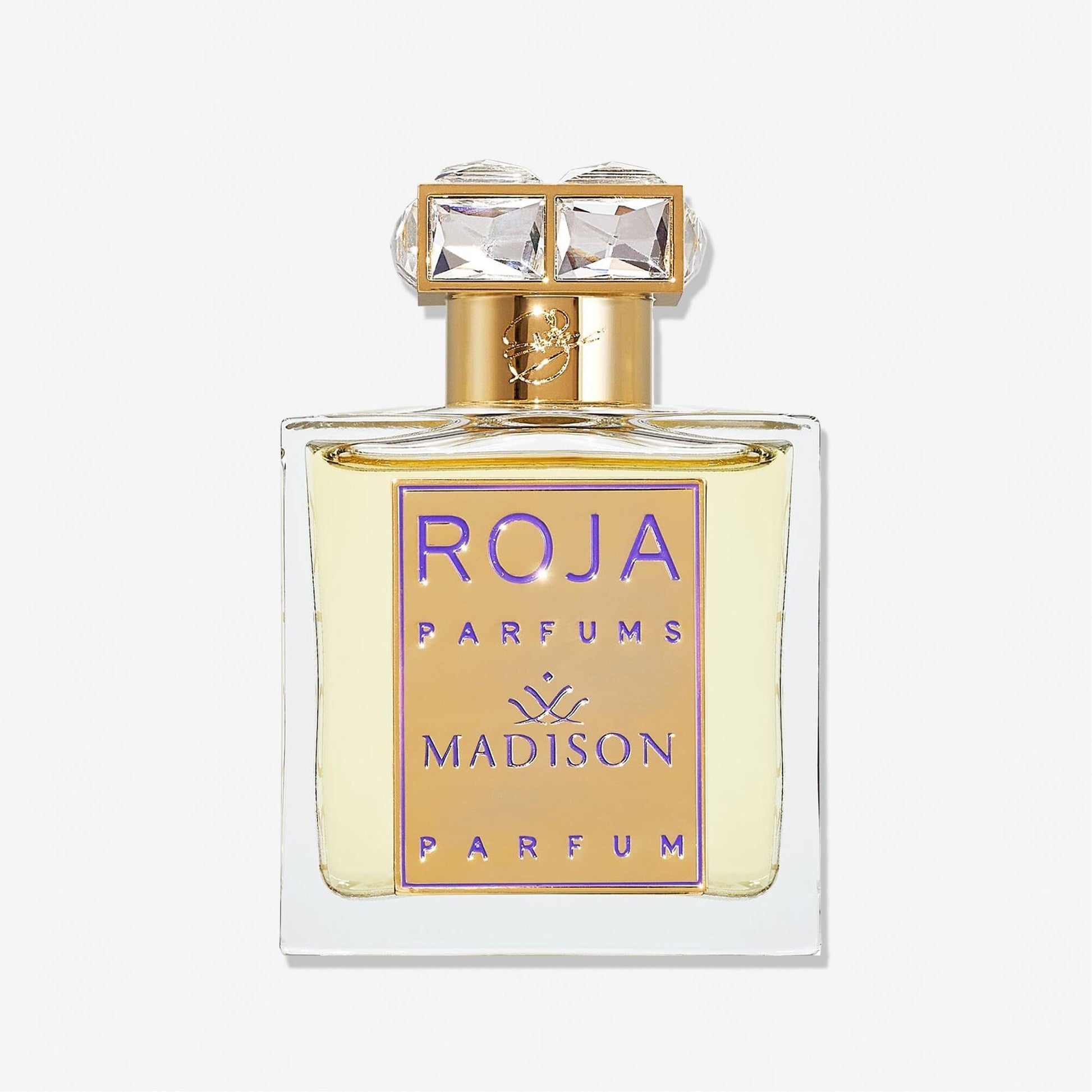 A clear glass bottle labeled Roja Parfums Madison Pour Femme features a gold and purple front plate and a cap adorned with two square, crystal-like gems, hinting at an elegant rose perfume with subtle notes of sandalwood.