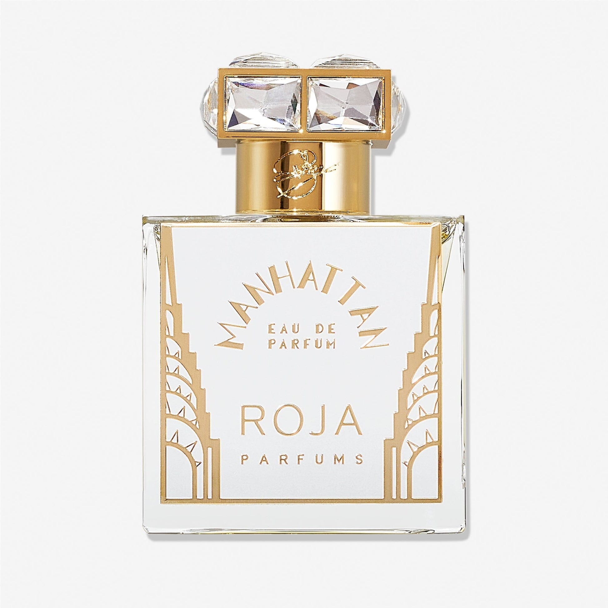Roja Parfums Manhattan Eau De Parfum comes in a clear glass bottle with gold accents, an Art Deco design, and a gold cap adorned with two crystal-like squares, capturing the essence of cedarwood in every spray.
