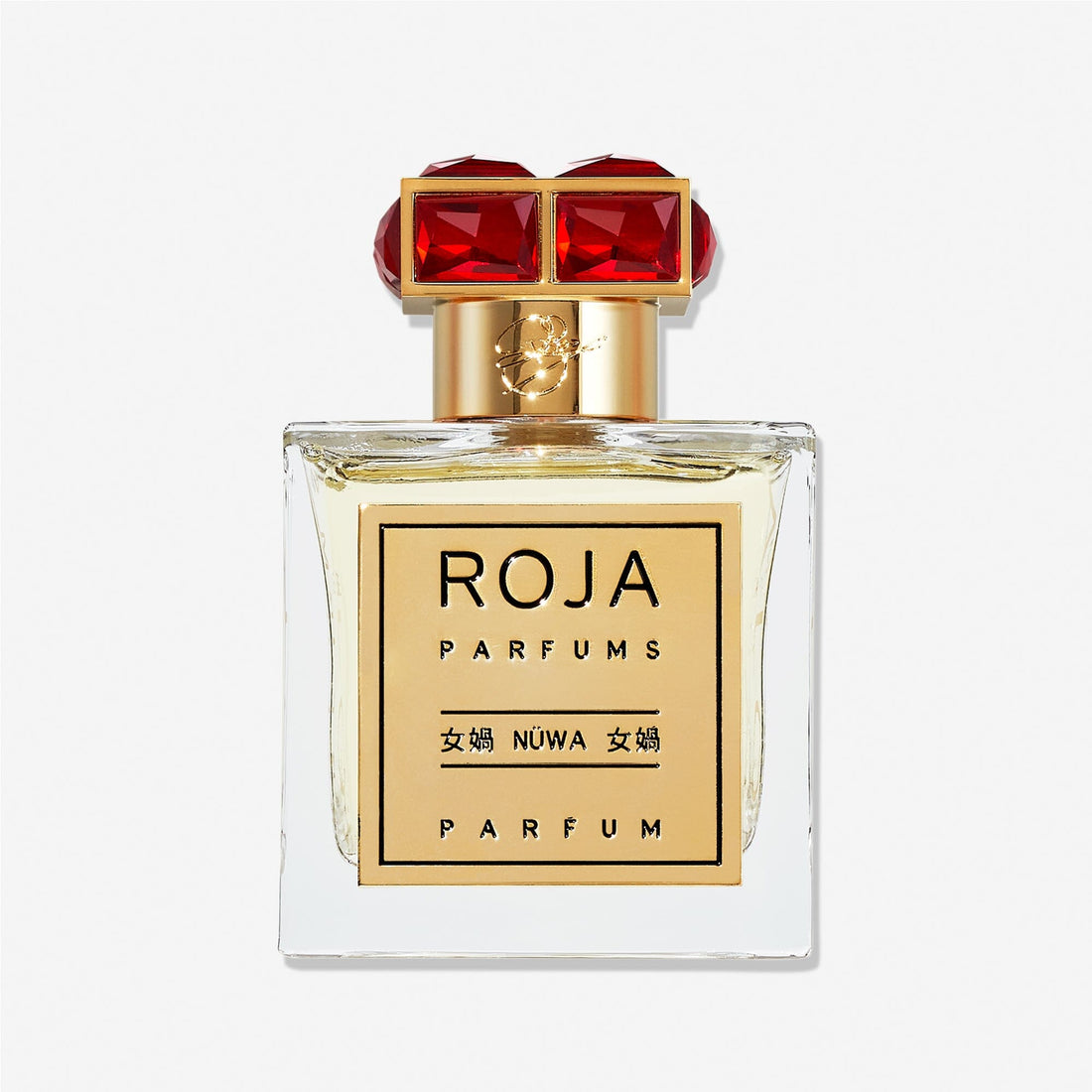A clear glass Roja Parfums NüWa bottle with a gold label in English and Chinese, topped with a gold cap featuring two large red gemstones, reflects the warm richness of sandalwood inside.