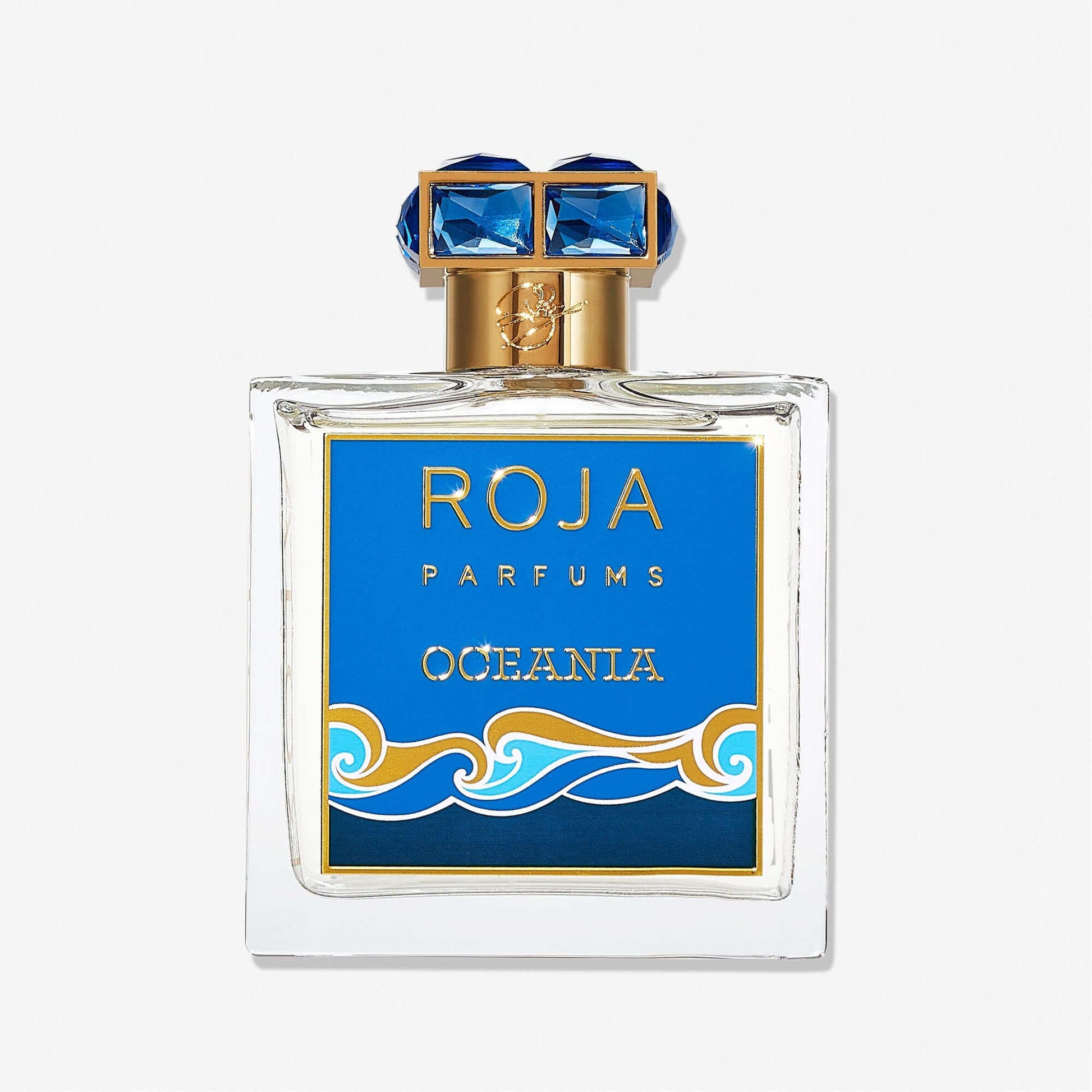 A square glass bottle of Roja Parfums Oceania features a blue and gold label with ocean wave graphics, topped with a gold cap adorned with blue accents, reflecting the fragrance’s fresh citrus character.