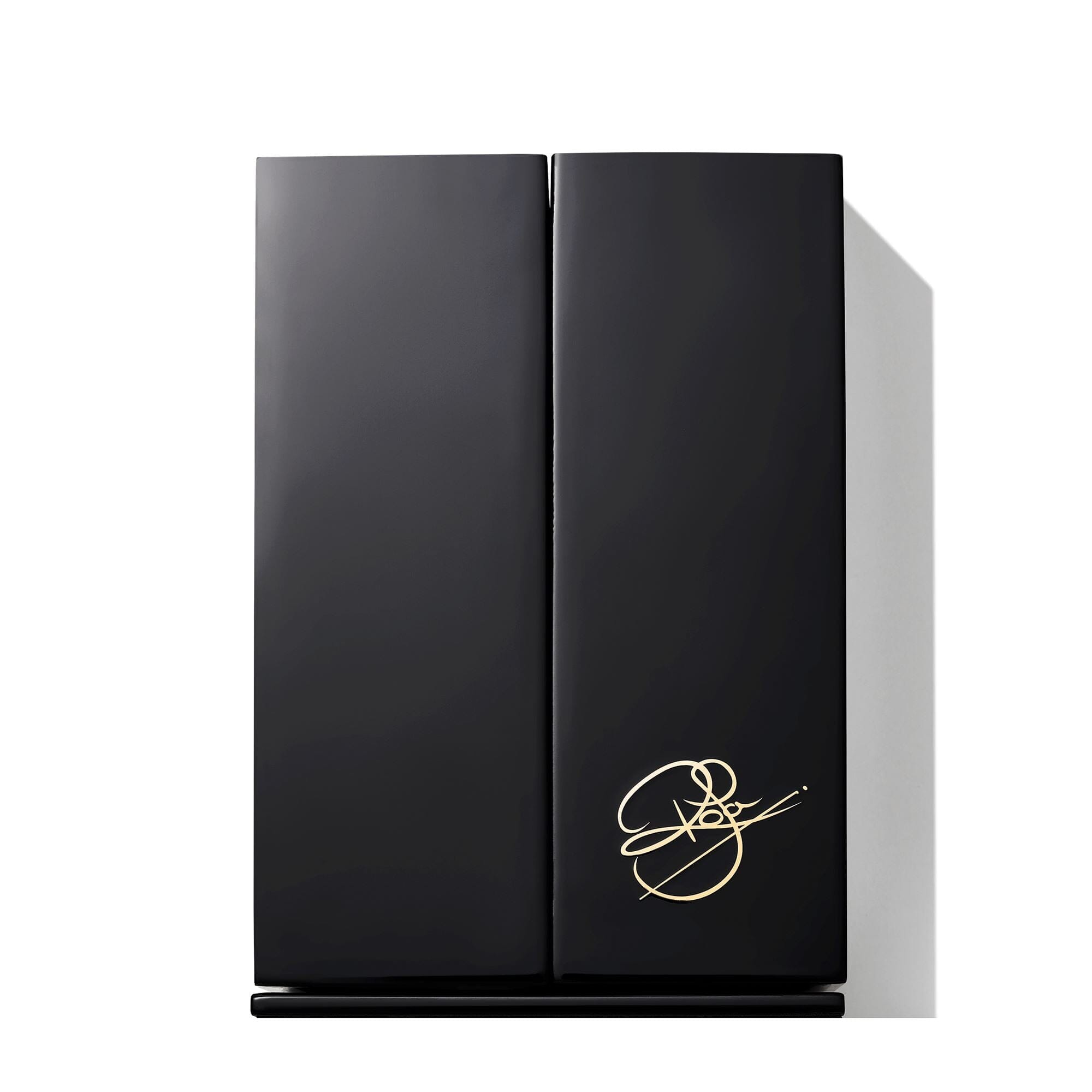 A sleek, black rectangular box with a gold signature design in the lower right corner, casting a shadow to the right on a white background.