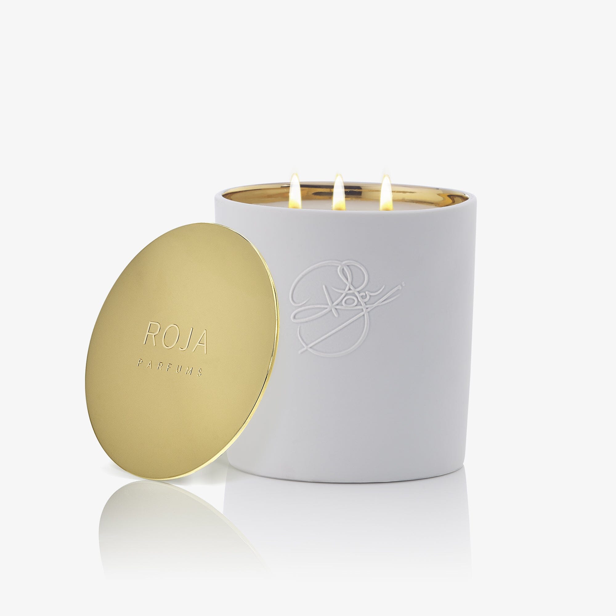 Peony Of Luoyang by Roja Parfums: a white candle with a gold embossed lid and signature logo, glowing with three flames. This exquisite scented candle fills your home with an elegant floral fragrance.