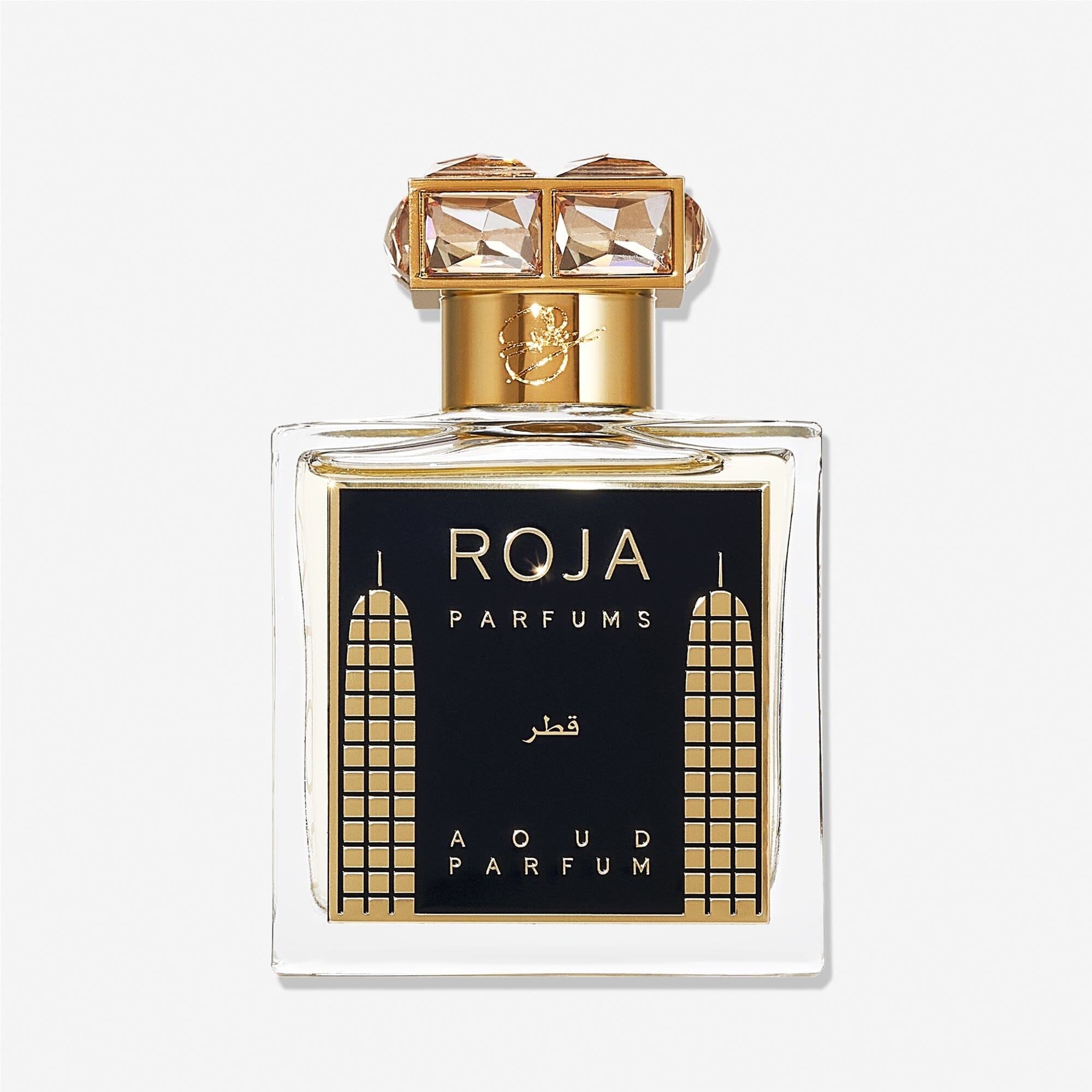 A luxury Roja Parfums Qatar perfume bottle features gold accents, geometric designs, and a crystal-studded gold cap—evoking notes of peach and pear in its lavish presentation.