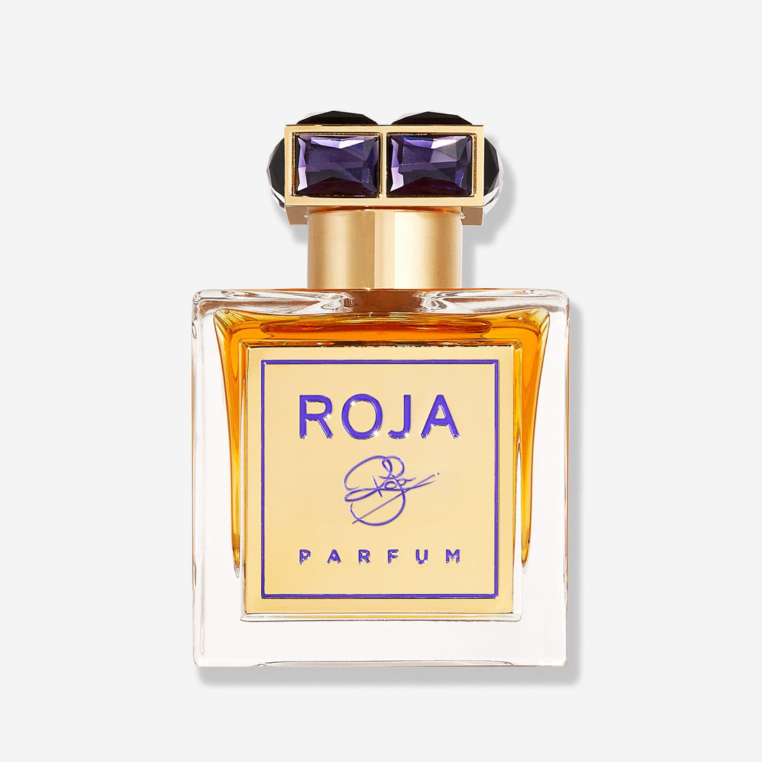 A glass bottle of ROJA by Roja Parfums, featuring amber liquid, a gold label with purple text, and a decorative black and gold geometric cap, set against a plain light background.