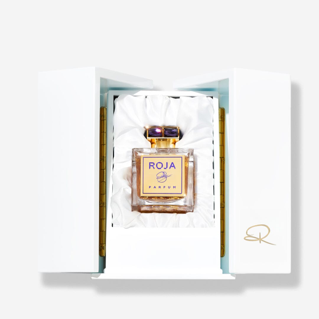 A luxurious ROJA perfume bottle from Roja Parfums, featuring a Chypré fragrance, stands upright in a white satin-lined box with gold accents and an embossed SR signature on the open lid.