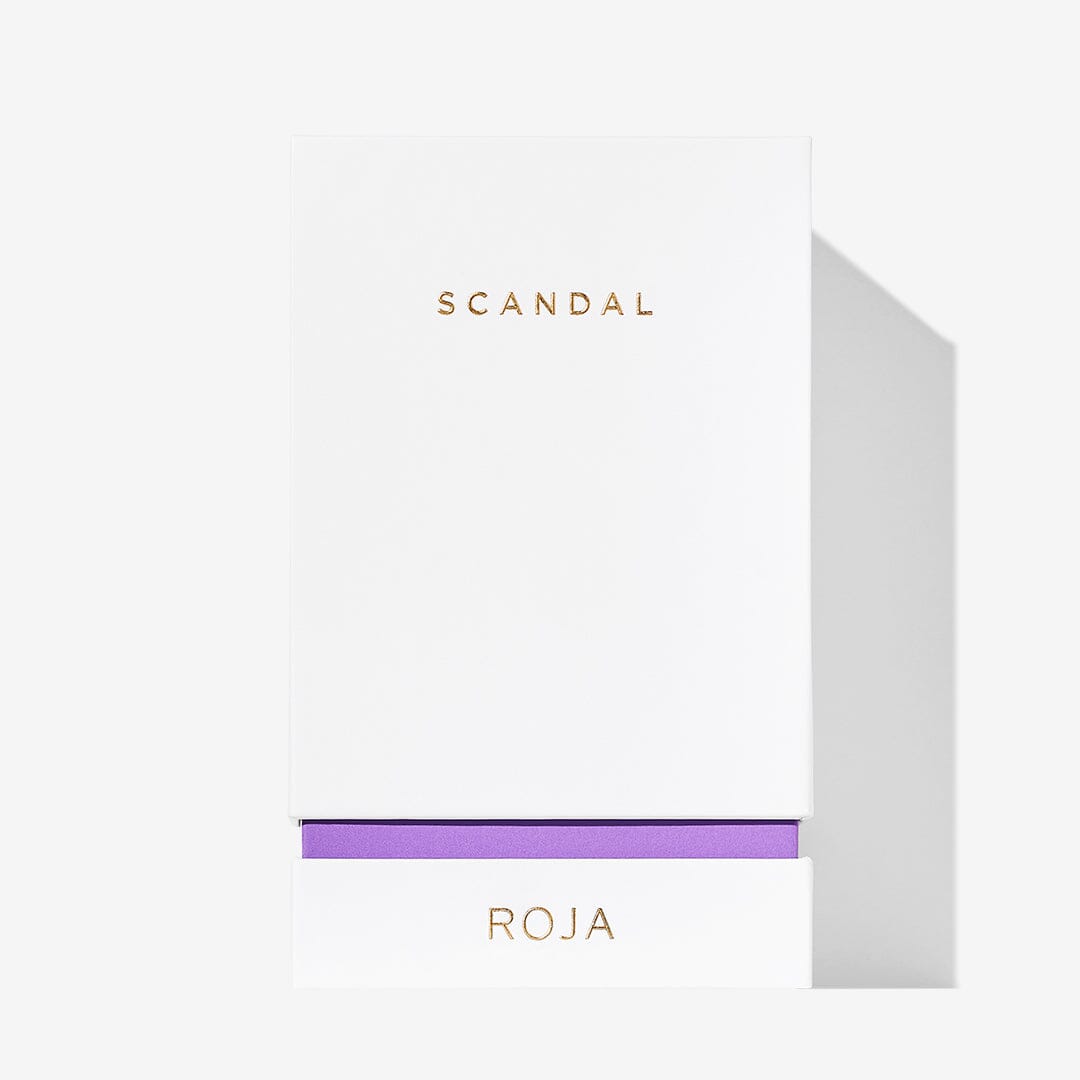 A minimalist white box displays SCANDAL POUR FEMME in gold at the top and ROJA PARFUMS above a purple accent, hinting at this scandalous sandalwood musk fragrance, all set against a clean white background.