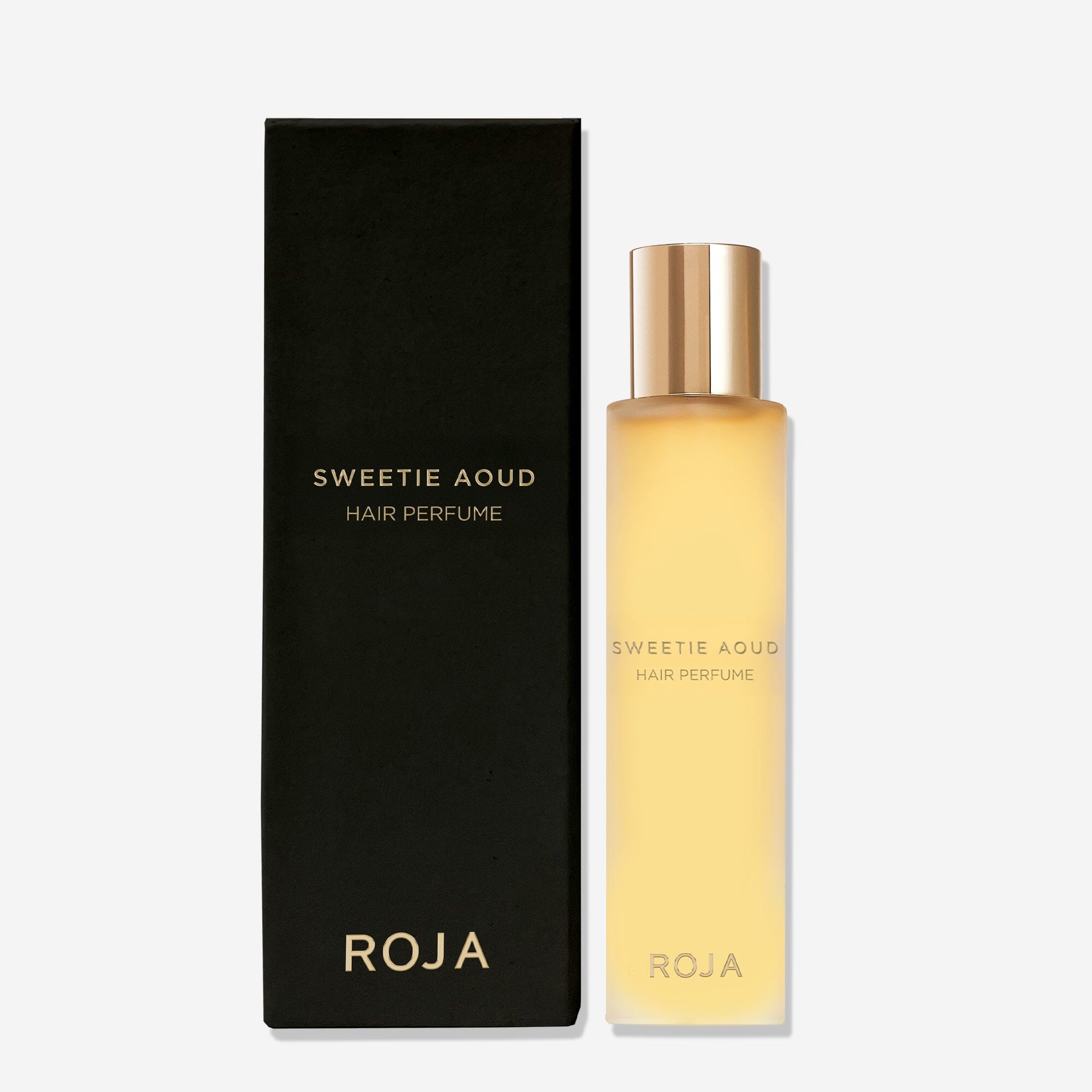 A matte black box labeled Sweetie Aoud Hair Perfume by Roja Parfums sits beside a frosted bottle with a gold cap and gold text, both on a plain white background—showcasing this luxurious gourmand perfume with rich agarwood notes.