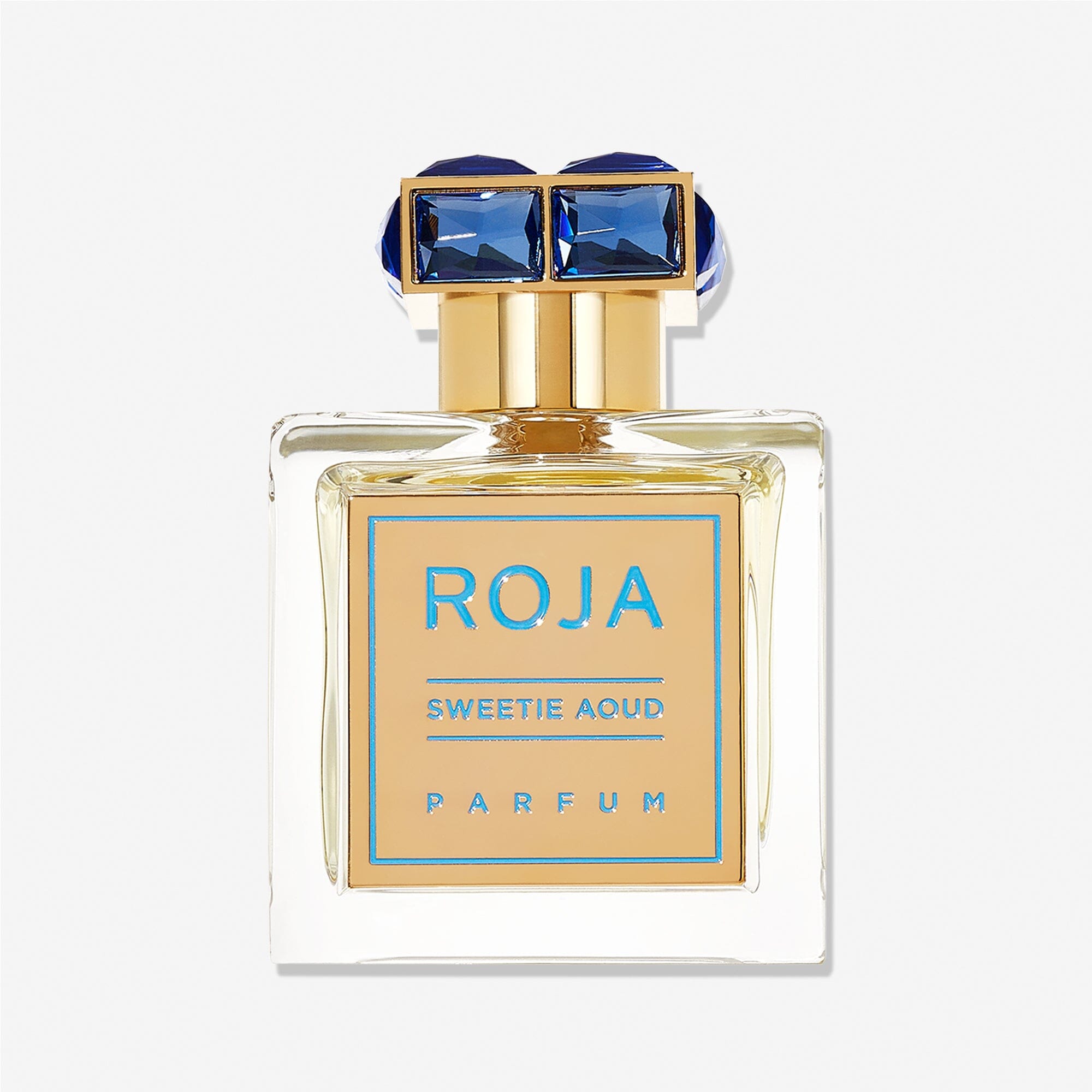 A clear glass bottle labeled Sweetie Aoud by Roja Parfums, with a gold label and cap topped by two blue gem-like accents. The parfum features oud and patisserie accords. Set against a plain white background.