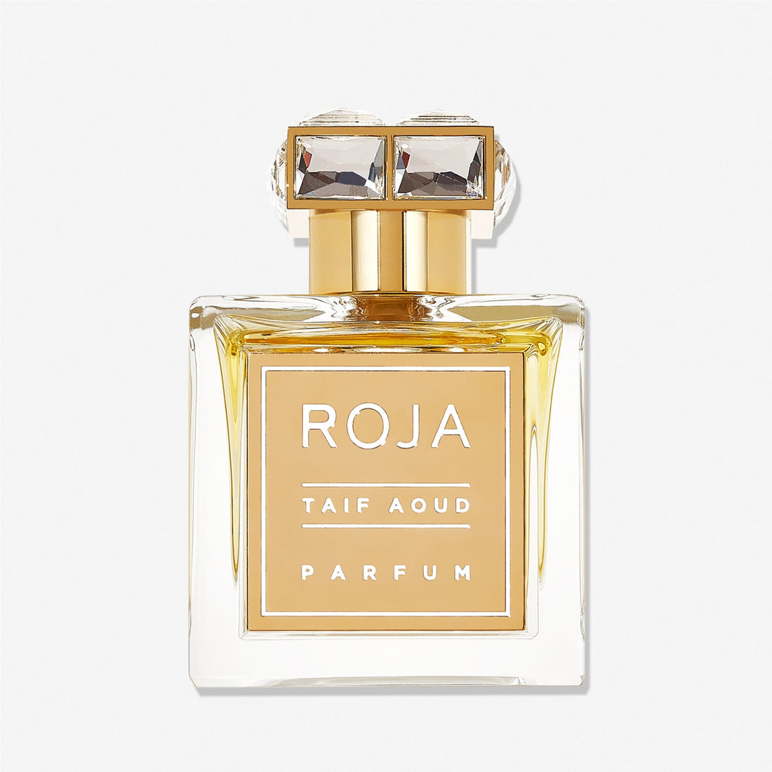 A clear, rectangular glass bottle of Roja Parfums Taif Aoud features gold accents, a gold label, and a gold cap set with two large square gemstones—reflecting the fragrance’s rose and aoud inspiration.