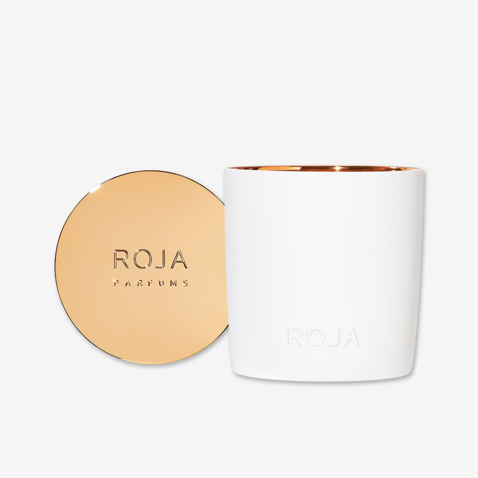The Roja Parfums London candle features a white jar with an embossed "ROJA" on the front and a metallic gold lid engraved with "ROJA PARFUMS," evoking London nightlife. Both are presented against a plain white background.