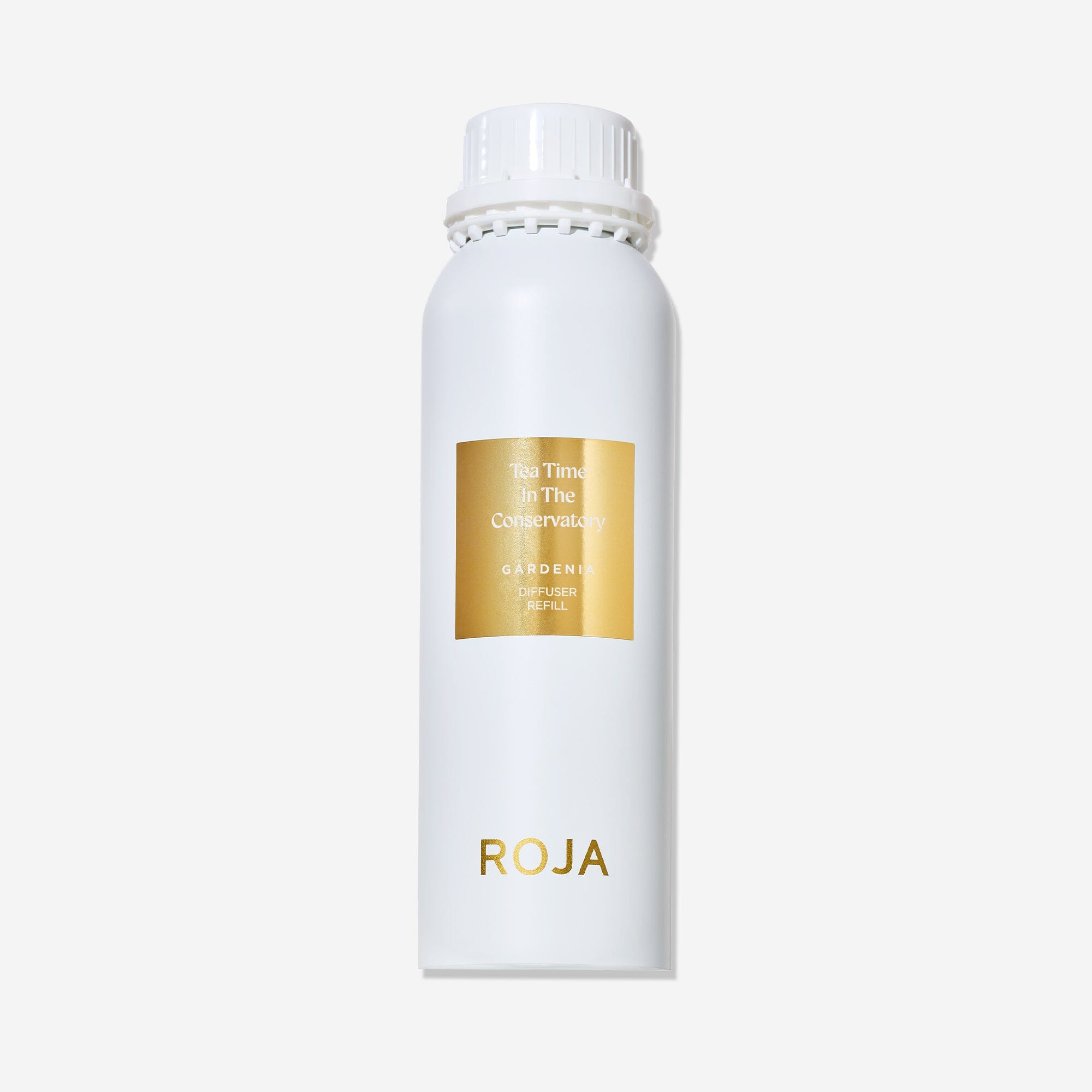 A white cylindrical bottle with a white cap and gold label displays "Tea Time In The Conservatory" by Roja Parfums, evoking the charm of an English country garden and the elegance of afternoon tea.