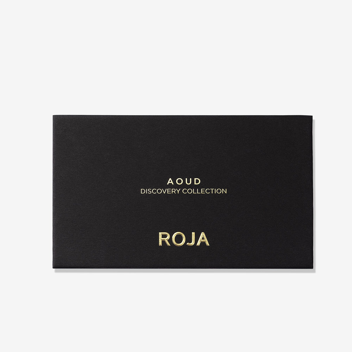 A sleek black rectangular box with gold text displays “The Aoud Discovery Collection” and “Roja Parfums” on the front, captured against a crisp white background—a refined prelude to the renowned Aoud Discovery Collection, inviting you to discover an expertly selected array of oud fragrances reminiscent of Arabian opulence.