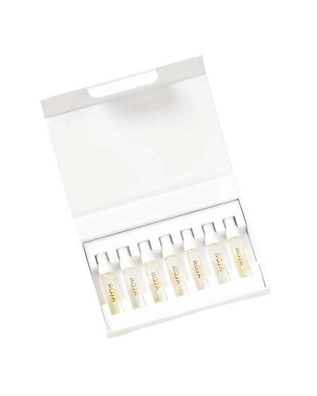 An open white box containing eight small transparent vials labeled ROJA with clear liquid inside, neatly arranged in a single row against a plain white background—this Signature Discovery Collection by Roja Parfums embodies olfactive art at its finest.