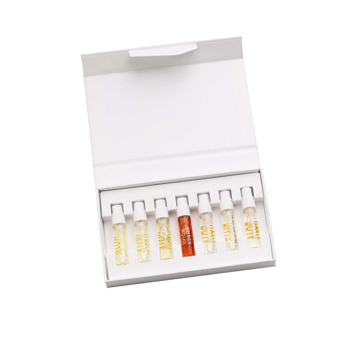 An open white box displaying nine small perfume sample vials—eight clear and one orange—arranged in a row against a white background showcases The Signatures Discovery Collection by Roja Parfums. This luxury perfume sample set invites you to explore olfactive art at its finest.